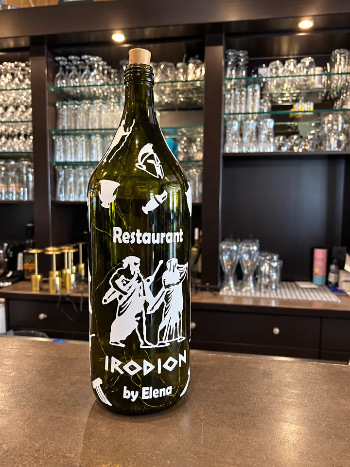 Eine grüne Flasche auf der Theke mit dem Aufdruck Restaurant Irodion by Elena.